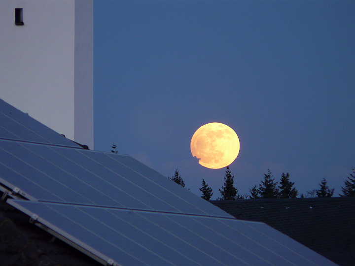 Der Mond ist vollständig sichtbar, rötlich und etwas eiförmig